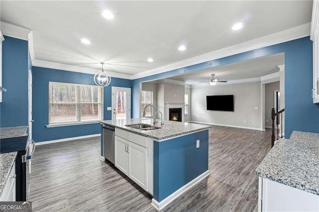 kitchen with sink, white cabinetry, hanging light fixtures, stainless steel appliances, and a kitchen island with sink