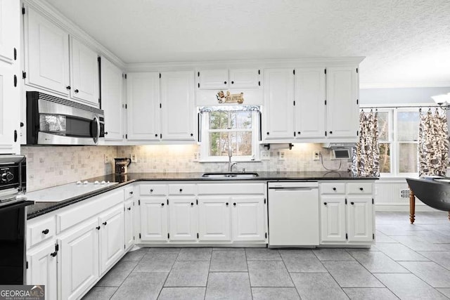 kitchen with sink, white dishwasher, tasteful backsplash, white cabinets, and oven