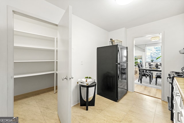 interior space with black refrigerator, gas range oven, and light tile patterned flooring