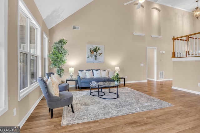 living room with wood finished floors, high vaulted ceiling, baseboards, and visible vents