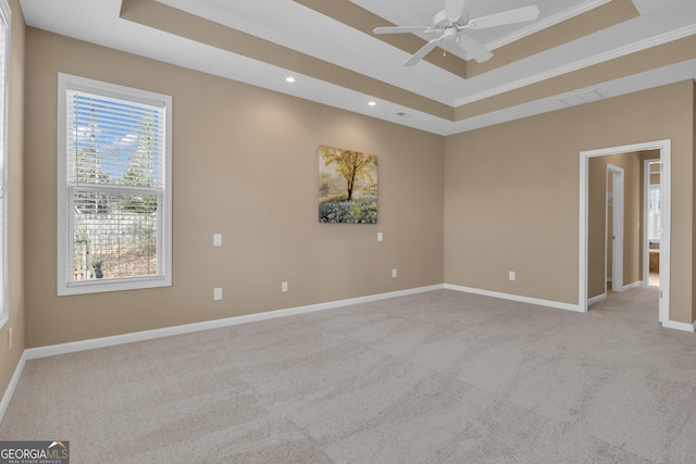 empty room with crown molding, baseboards, a raised ceiling, and light carpet