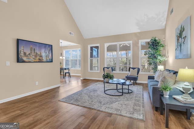 living room with a healthy amount of sunlight, high vaulted ceiling, and wood finished floors