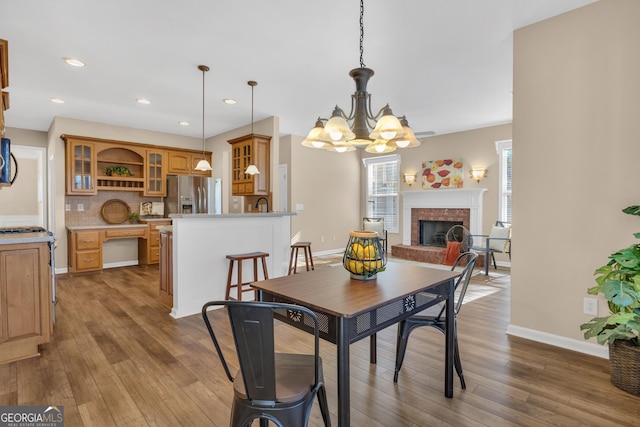 dining room with a fireplace, recessed lighting, a chandelier, wood finished floors, and baseboards