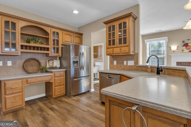 kitchen with built in desk, light countertops, a sink, stainless steel appliances, and decorative backsplash