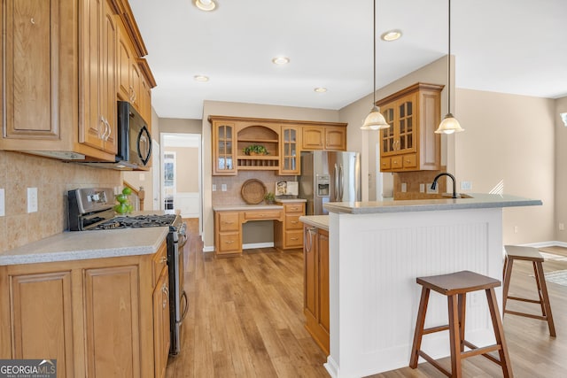 kitchen with tasteful backsplash, appliances with stainless steel finishes, a breakfast bar, light wood-style floors, and a peninsula