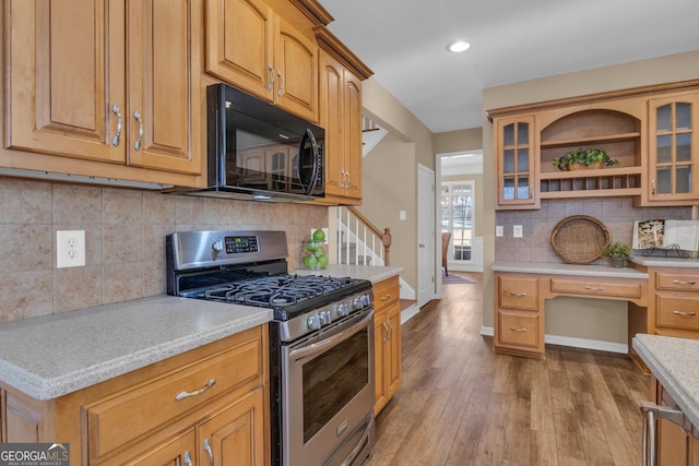 kitchen with black microwave, tasteful backsplash, gas range, light countertops, and light wood finished floors