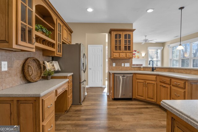 kitchen with a ceiling fan, brown cabinetry, decorative backsplash, dishwasher, and a sink