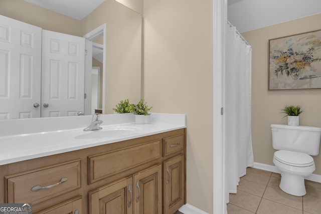 bathroom with toilet, vanity, baseboards, and tile patterned flooring