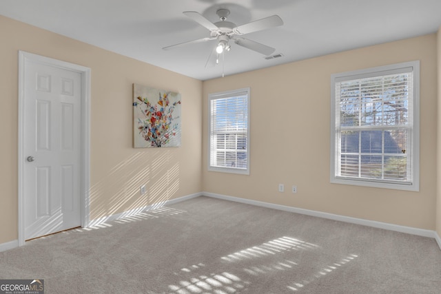 carpeted spare room featuring visible vents, baseboards, and ceiling fan