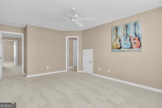 empty room featuring light colored carpet, baseboards, and ceiling fan