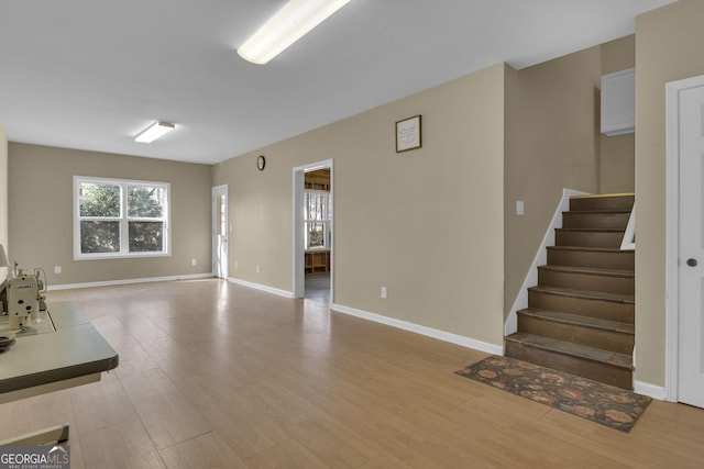 living room with light wood-style flooring, baseboards, and stairs