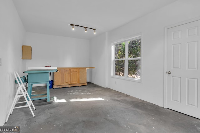 interior space with track lighting and unfinished concrete flooring