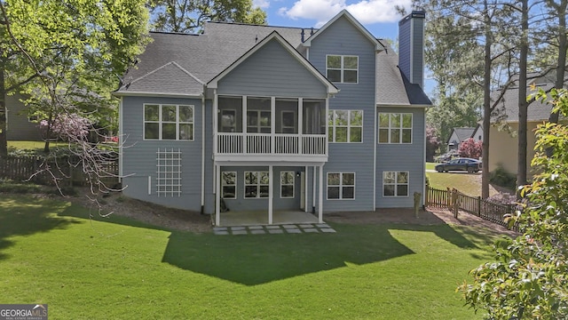 rear view of property featuring a sunroom, a yard, a patio, fence, and a chimney