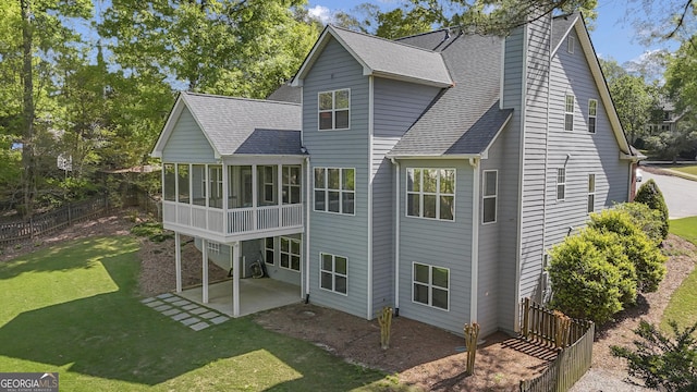 back of house with a yard, a patio, a sunroom, and roof with shingles