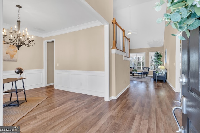 entrance foyer with a notable chandelier, crown molding, and wood finished floors