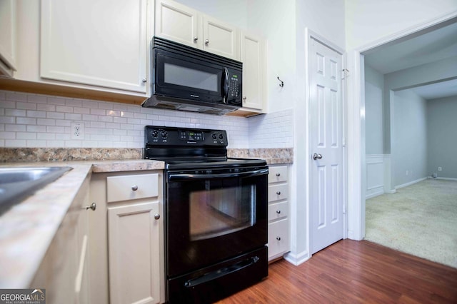 kitchen featuring white cabinetry, dark wood-type flooring, decorative backsplash, and black appliances