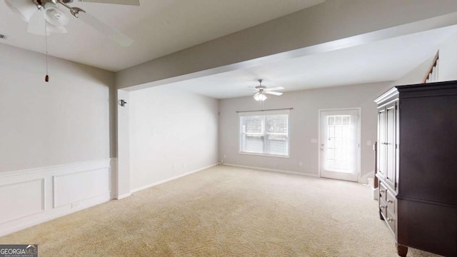 unfurnished living room with light colored carpet and ceiling fan