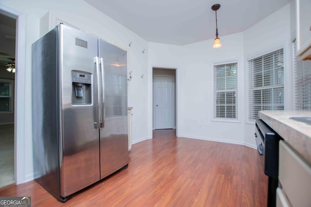 kitchen featuring hanging light fixtures, wood-type flooring, black dishwasher, and stainless steel fridge with ice dispenser