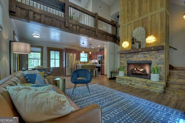 living room with dark hardwood / wood-style flooring, a towering ceiling, and a fireplace