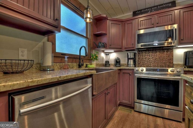 kitchen featuring hanging light fixtures, backsplash, stainless steel appliances, and light stone countertops