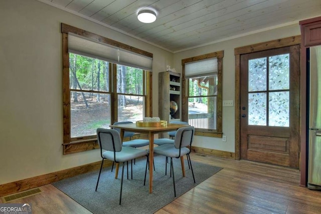 dining space with ornamental molding, wood-type flooring, and wooden ceiling