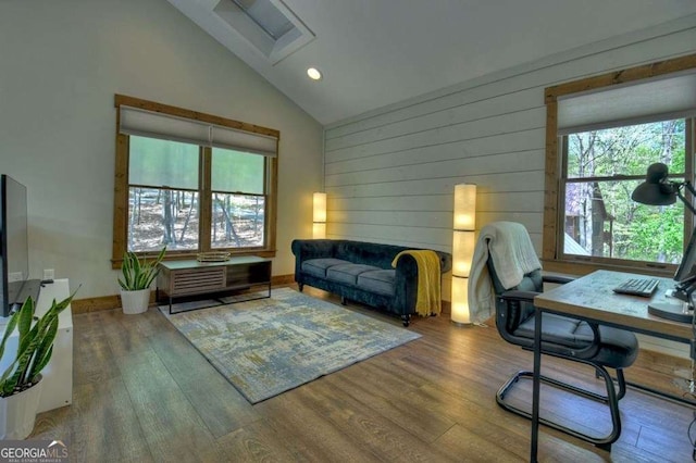 office area with wood-type flooring, high vaulted ceiling, a wealth of natural light, and wooden walls