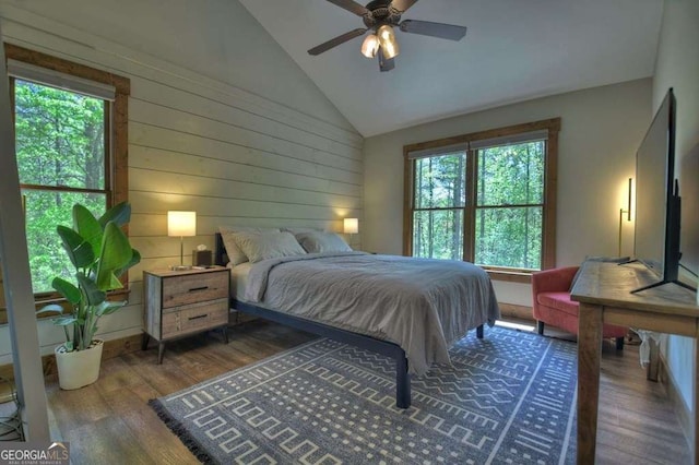 bedroom with wooden walls, ceiling fan, lofted ceiling, and dark hardwood / wood-style floors