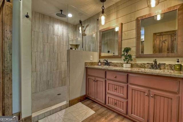 bathroom with hardwood / wood-style flooring, vanity, and tiled shower