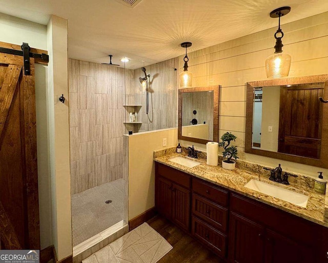 bathroom featuring hardwood / wood-style flooring, vanity, and a tile shower