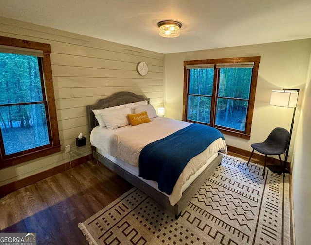 bedroom featuring dark wood-type flooring and wood walls