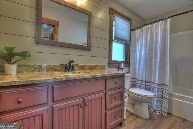 full bathroom with wooden walls, vanity, wood-type flooring, toilet, and shower / bath combo with shower curtain