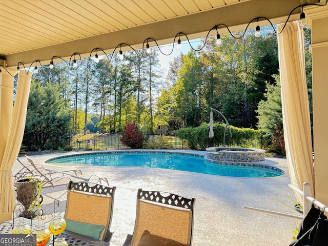 view of pool featuring a pool with connected hot tub, a patio area, and fence