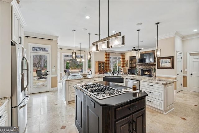 kitchen with stainless steel appliances, ornamental molding, white cabinets, a kitchen island, and decorative light fixtures