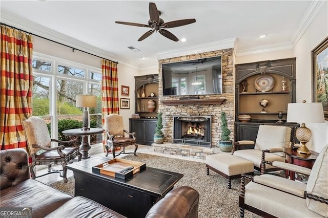 living room with crown molding, ceiling fan, a fireplace, and built in shelves