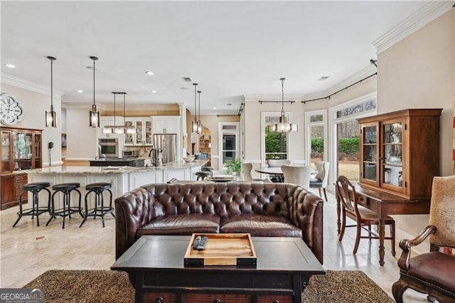 living room with ornamental molding, sink, and a chandelier