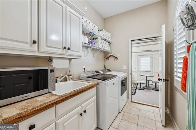 laundry area featuring cabinets, light tile patterned flooring, sink, and independent washer and dryer