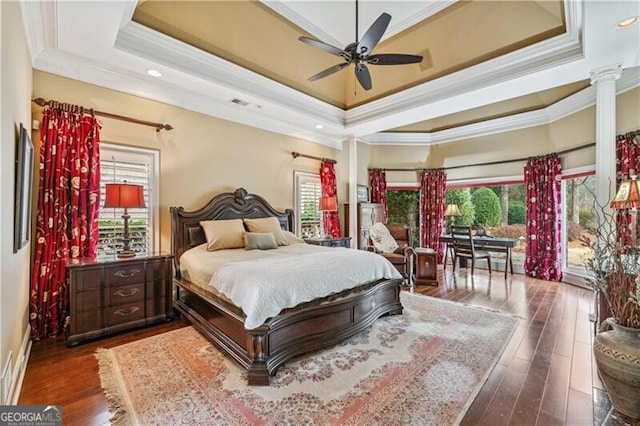 bedroom with multiple windows, ornamental molding, dark hardwood / wood-style flooring, and a tray ceiling