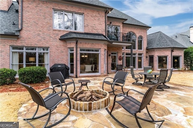 9135 Etching Overlook, Johns Creek, GA 30097 - back of property featuring a balcony, a fire pit, a patio area, brick siding, and a shingled roof