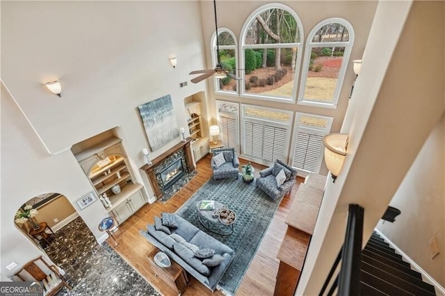 living room with hardwood / wood-style flooring, ceiling fan, and a high ceiling