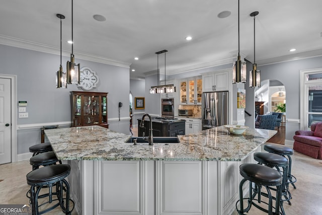 9135 Etching Overlook, Johns Creek, GA 30097 - kitchen featuring appliances with stainless steel finishes, crown molding, arched walkways, recessed lighting, and a kitchen bar