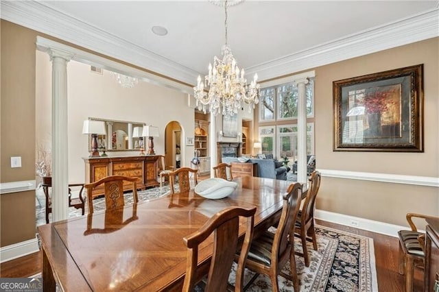 dining room with dark hardwood / wood-style flooring, crown molding, and ornate columns