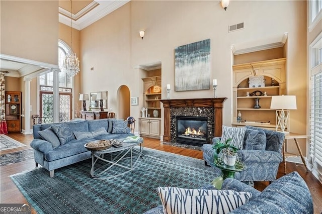 living room with hardwood / wood-style flooring, built in features, ornamental molding, and a premium fireplace