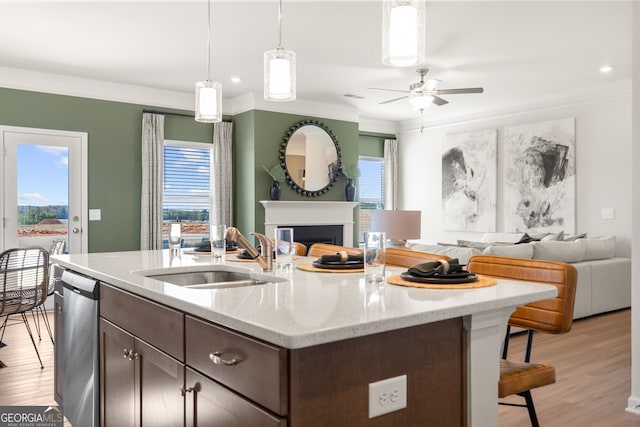 kitchen featuring sink, dishwasher, dark brown cabinetry, light stone countertops, and decorative light fixtures