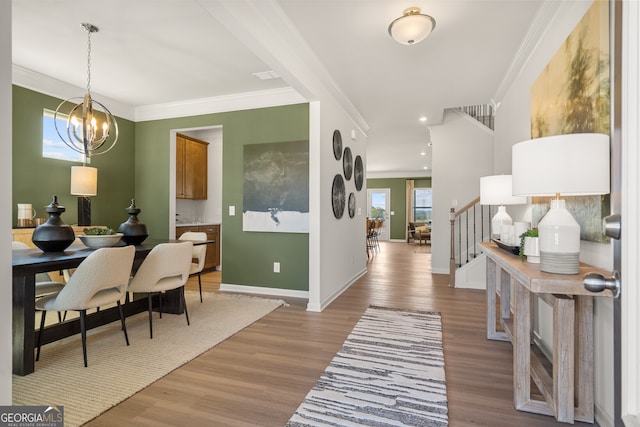 interior space with light hardwood / wood-style flooring, ornamental molding, and a chandelier