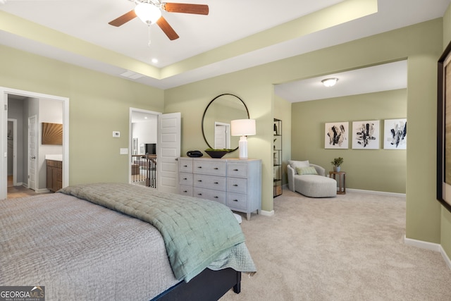 bedroom with a raised ceiling, light colored carpet, and ceiling fan