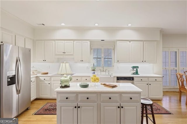 kitchen with sink, white cabinets, a center island, stainless steel appliances, and light wood-type flooring