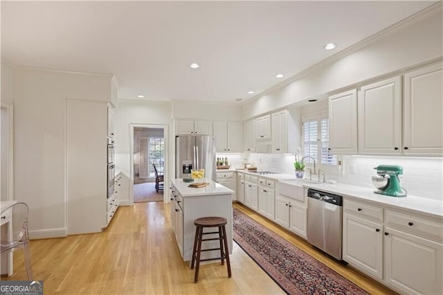 kitchen with white cabinetry, appliances with stainless steel finishes, a center island, and a kitchen breakfast bar