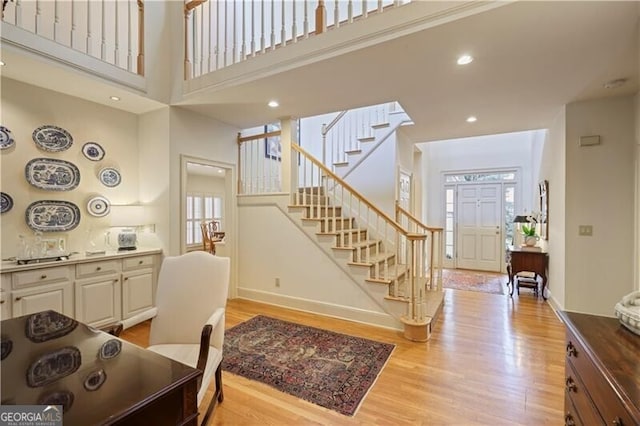 interior space with a towering ceiling and light hardwood / wood-style flooring