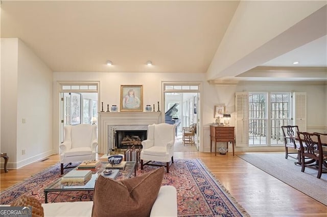 living room with a high end fireplace, light hardwood / wood-style flooring, and a wealth of natural light