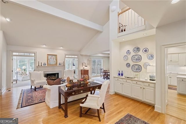 living room with high vaulted ceiling, beam ceiling, and light hardwood / wood-style floors